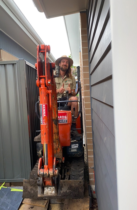 photos of landscape tradesman driving excavator down tight side property access